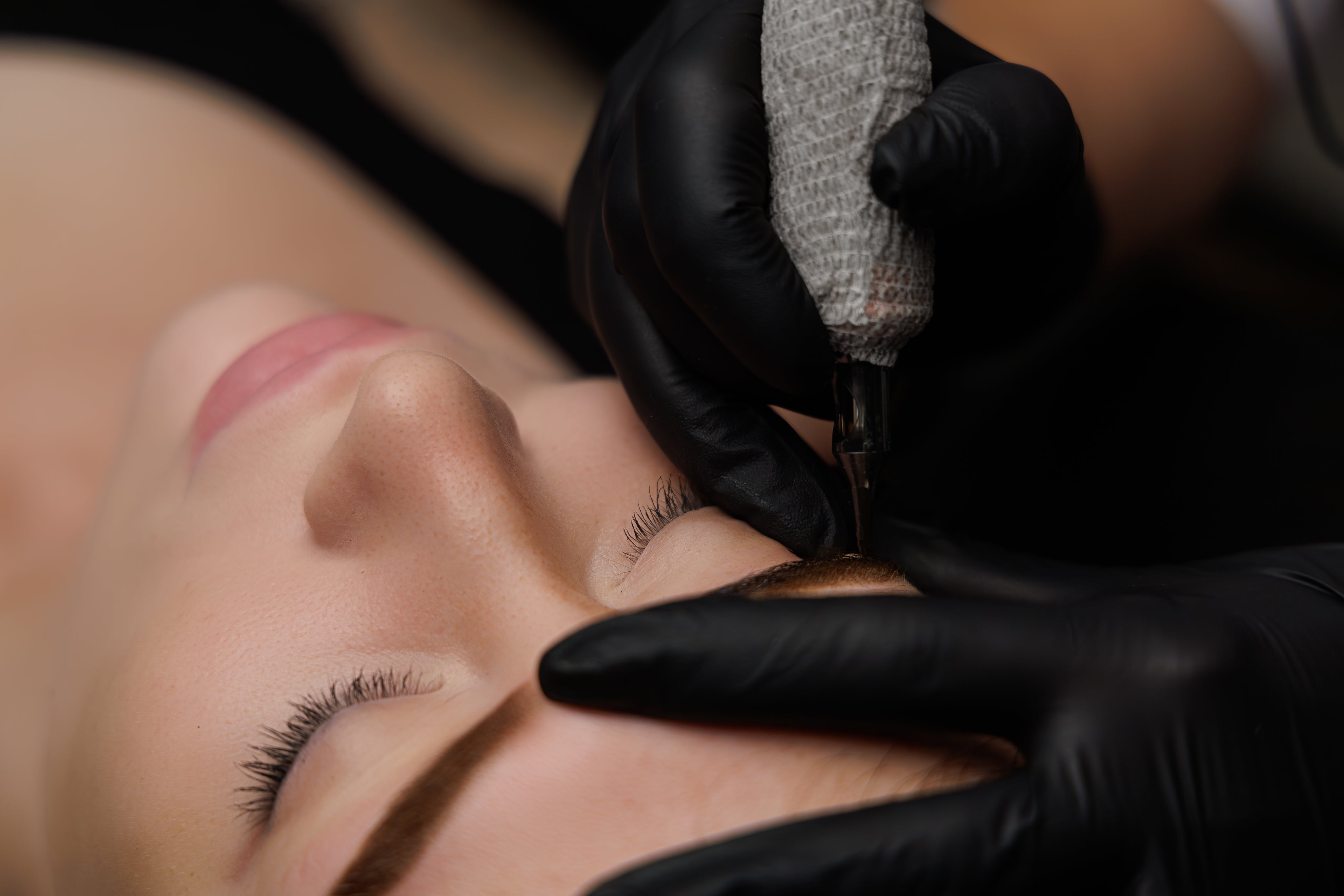 relaxed-girl-with-closed-eyes-lying-down-permanent-makeup-procedure-as-master-applies.jpg
